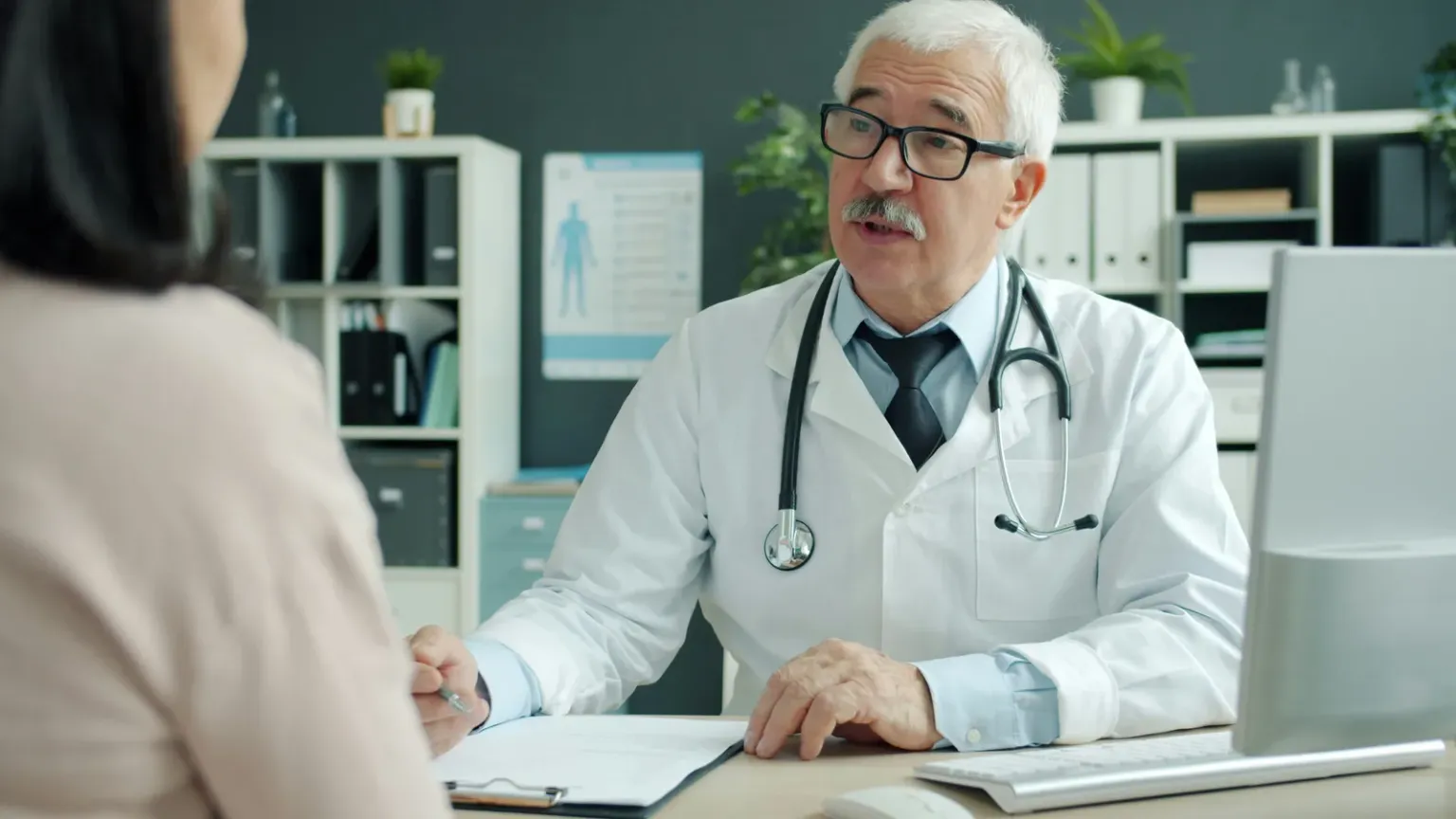 Doctor seated at a desk speaking with a patient