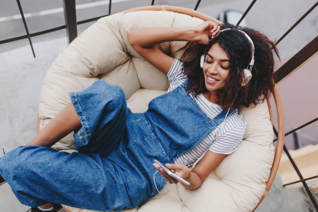 Listener relaxing in a chair with headphones and a phone