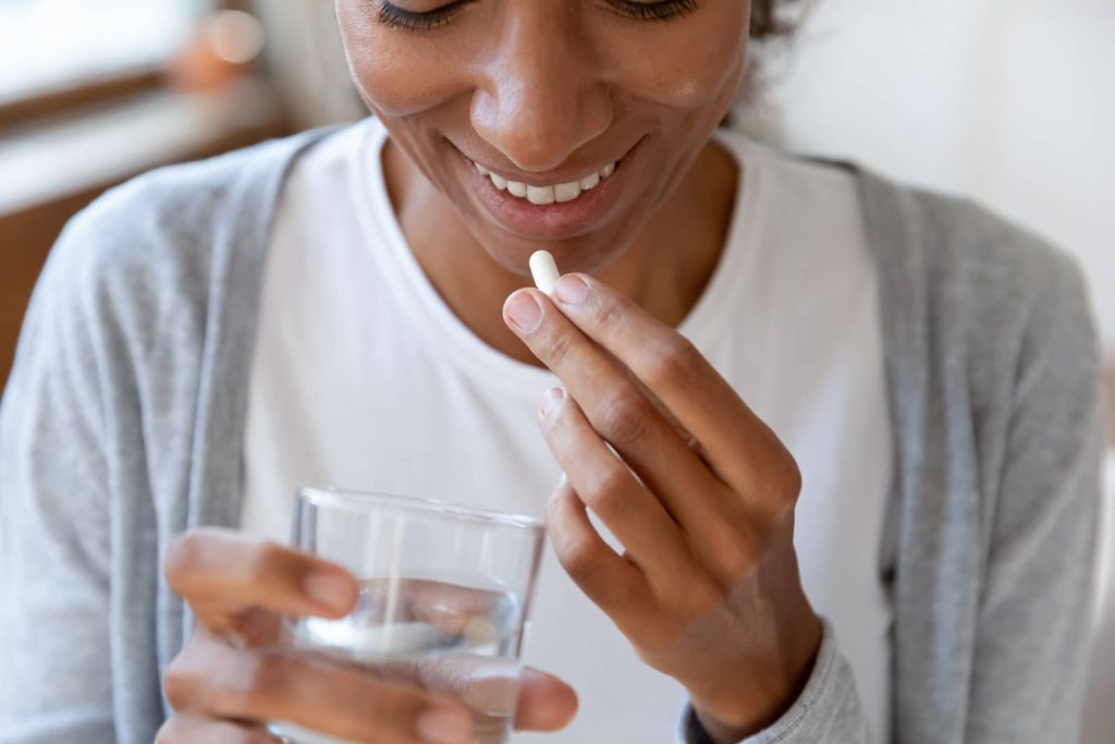 Woman taking a medication with a glass of water